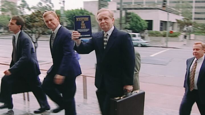 Gerald Flurry holds up a copy of Mystery of the Ages as he walks with his legal team