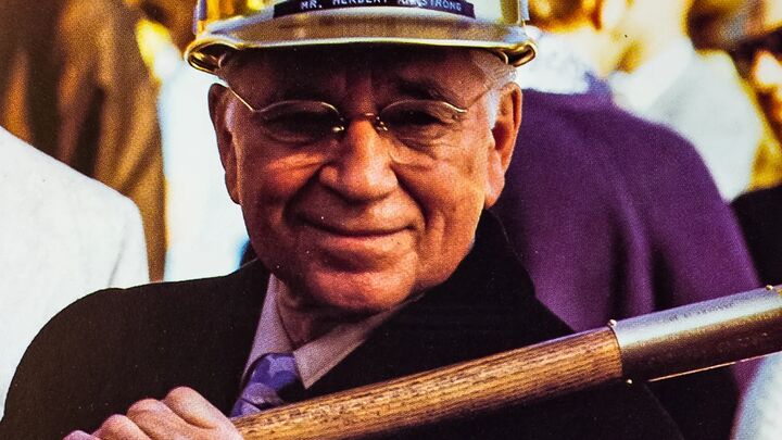 Herbert W. Armstrong in a hard hat, holding a ceremonial shovel