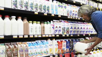 Mature woman reading milk label in supermarket, side view, close-up