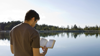 Man Reading Bible By Lake