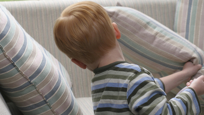 Boy looks under couch cushion