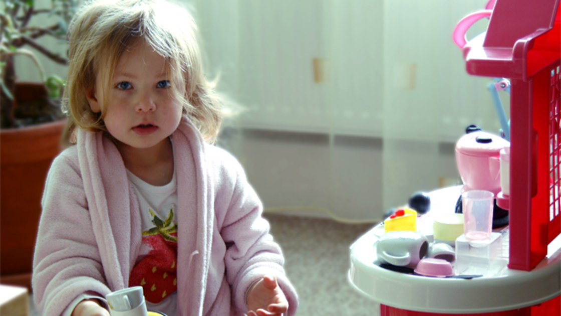 Little girl plays with pretend kitchen.