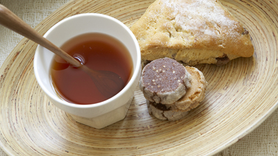 Pastries and cup of tea on wooden plate, close-up