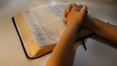 A photo of a person praying over their Bible.