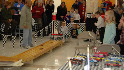 Anthony Morgan confirms race times in a 4-car heat while spectators look on. 