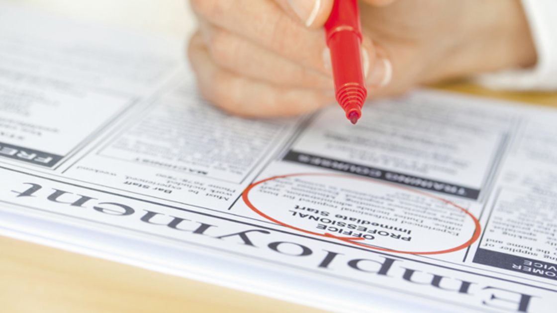 Hand with Red Pen Marking Job in Newspaper