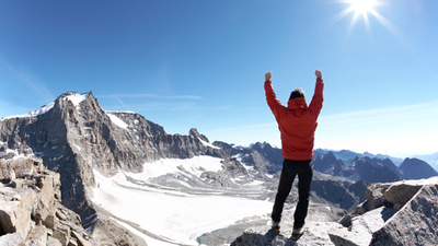 Sign of victory: climber on the top of the mountain. Gran Paradiso National Park, Italy