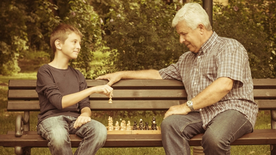 Grandfather and grandson playing chess in the park