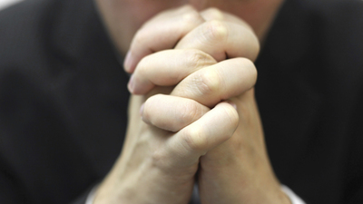 man folded his hands together, praying  with blurred face
