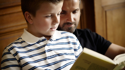 Father and son reading a book together.