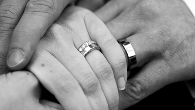 A close up image of a man and woman holding hands after marriage ceremony.