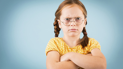 An upset girl crosses her arms and pouts.