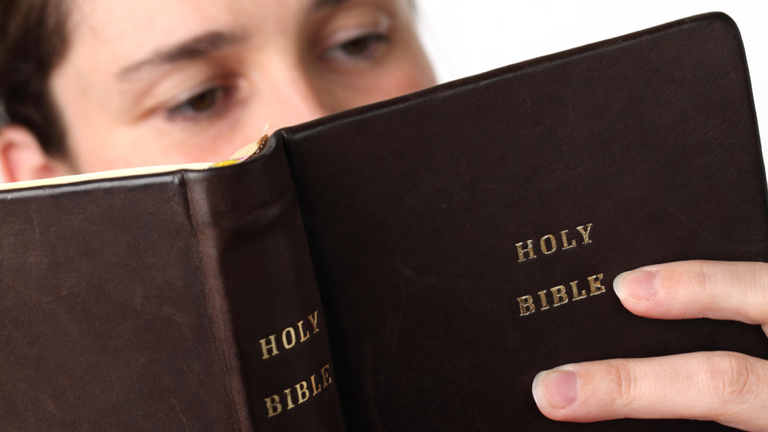 Young woman reading the Bible. Focus on the Bible