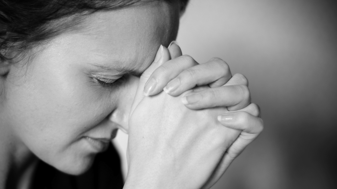 Anxious young woman rests her head on he hands in a stresfull moment. Very shallow DoF - focus is on hereyes and forehead.