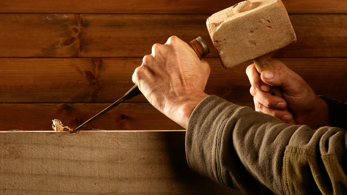 gouge wood chisel carpenter tool hammer in hand working wooden background