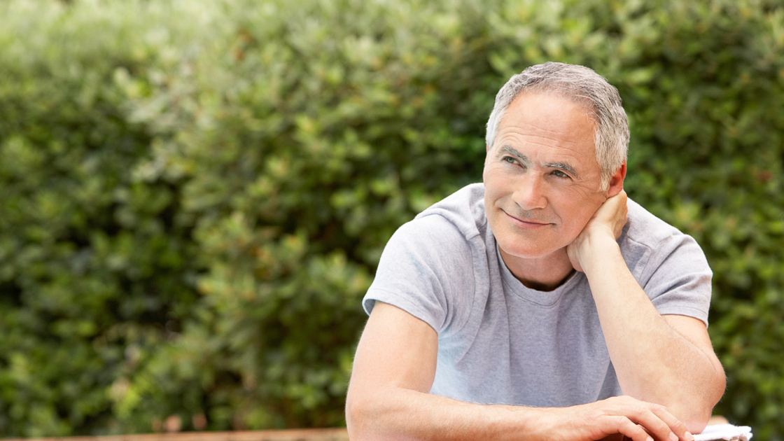 Happy middle aged man reclining by poolside