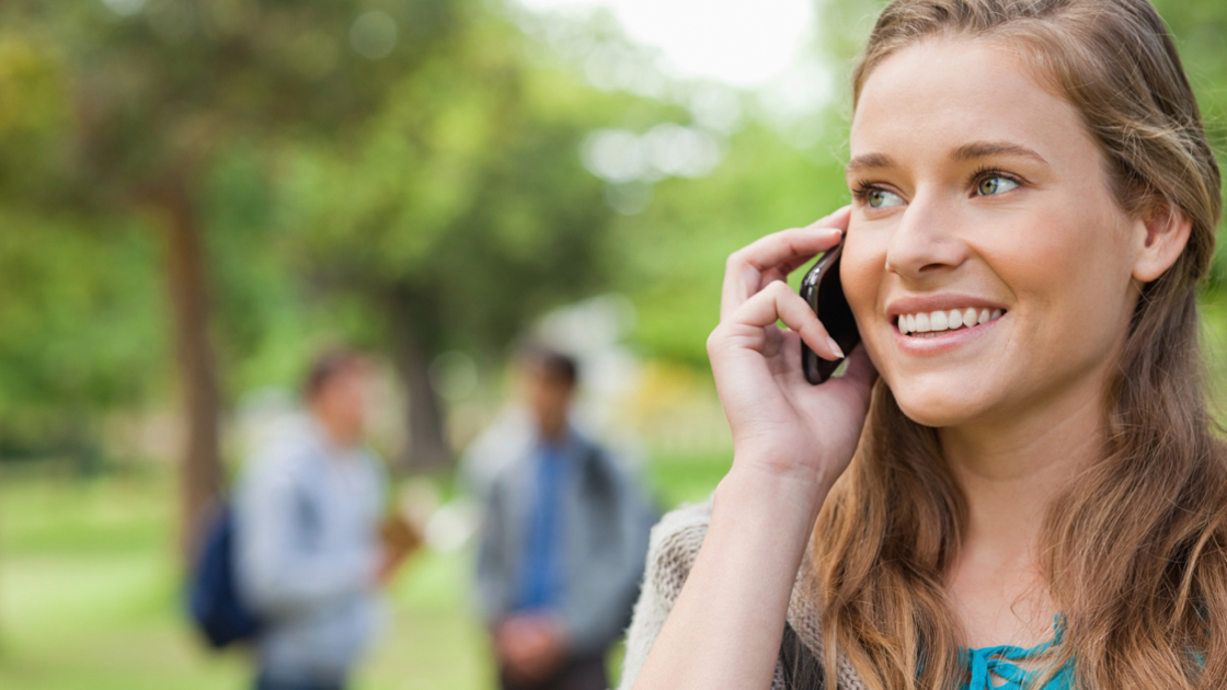 16x9 (Give the Gift of words)
Close up of a blonde student calling in a park with people in background