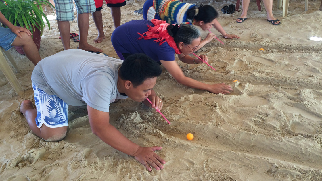 Members scramble on the sand for the pingpong blowing.