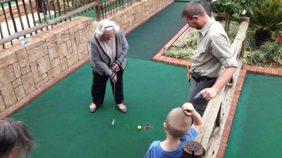 Mag Kotze putts on the green while Rohann and Zeo Smith look on.