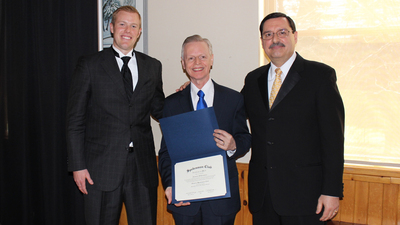 Local Elder David Weeks (left) and Regonial Director Fred Dattolo (right) congratulate club graduate Antonin Chiasson while he holds his graduation certificate.