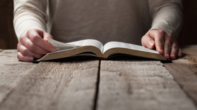 16x9(Sin is)
woman reading the bible in the darkness over wooden table