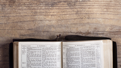 16x9(What is the Bible rated?)
Opened bible on a wooden desk background.