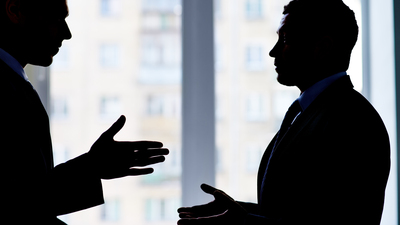 Back lit image of two businessmen arguing