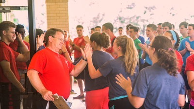 Mr. Burns gives campers high fives as they enter the dining hall