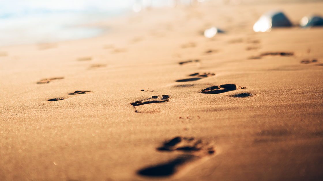 Family walking home from the sandy beach on Kefalonia Island (Avithos). Footsteps in the sand at sunset.