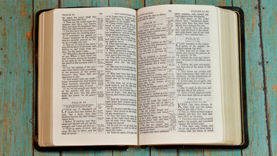 The holy Bible opened to the book of Psalm on a wooden plank rustic background