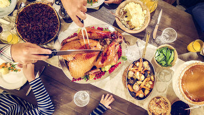 Family having traditional holiday dinner with stuffed turkey, mashed potatoes, cranberry sauce, vegetables pumpkin and pecan pie.