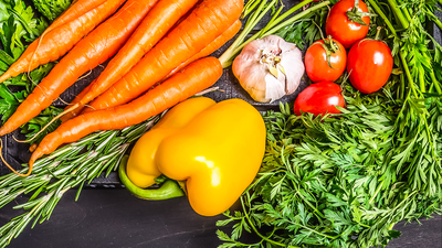 Colorful various organic farm vegetables carrots cherry tomatoes, garlic, cucumber, lemon, pepper, radish, wooden spoon salt pepper colored, oil wooden rustic background top view  border, place text