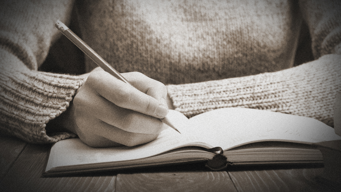 female hands with pencil writing on notebook.