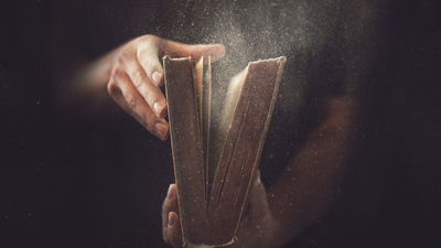 Holding an open book with dust coming out.