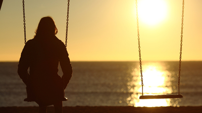 Lonely woman watching sunset alone in winter on the beach at sunset