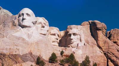 Mount Rushmore set against a bright cloud free blue sky.