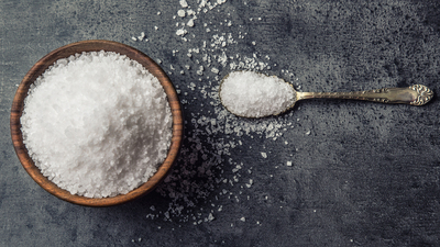 Salt. Coarse grained sea salt on granite - concrete  stone background with vintage spoon and wooden bowl.