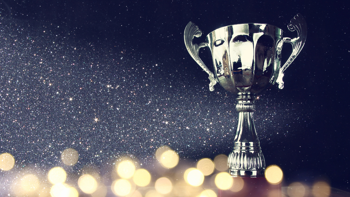 low key image of trophy over wooden table and dark background, with abstract shiny lights