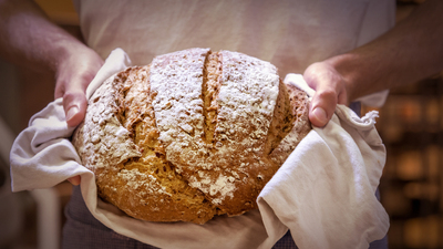 Baker shot in bakery, with warm bread just out of the oven