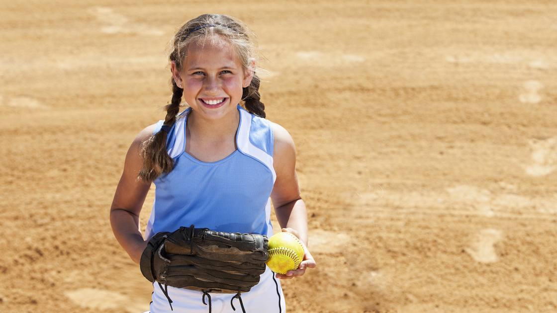 Girl (9 years) playing softball, standing on pitcher's mound.