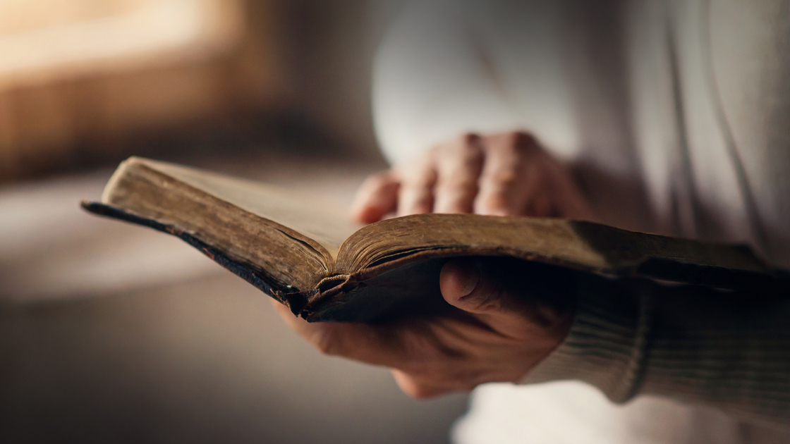 Unrecognizable woman holding a bible in her hands and praying