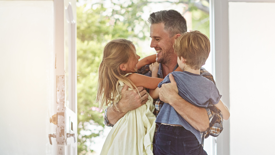 Shot of a father embracing his two children as he enters the house