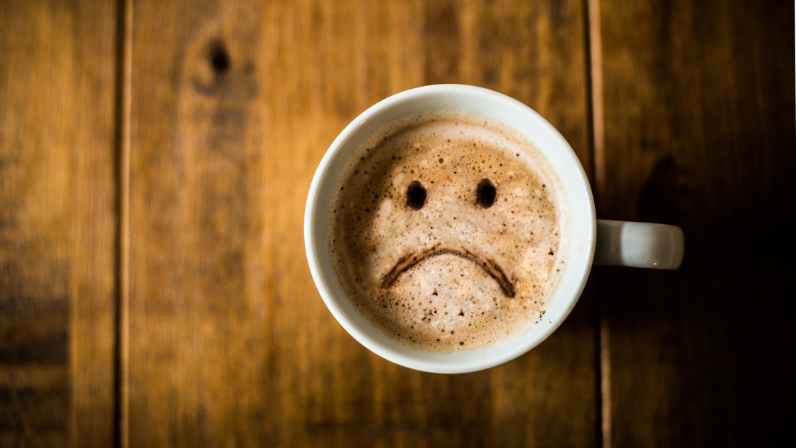 A sad looking Coffee Cup on a brown rustic table.