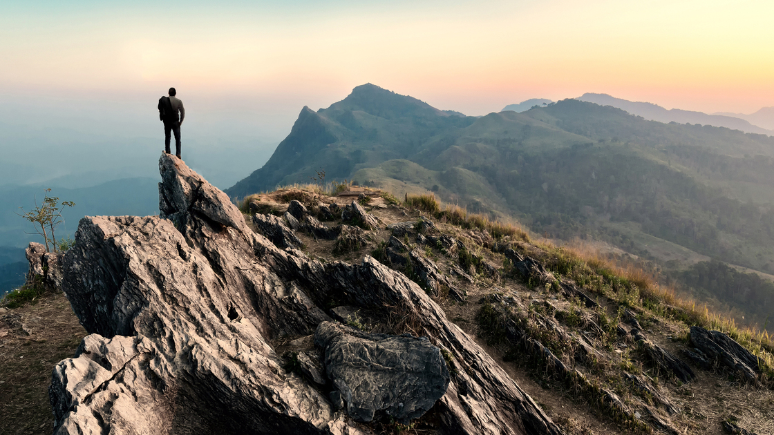 businessman hike on the peak of rocks mountain at sunset, success,winner, leader concept