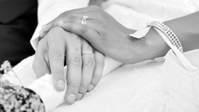 Husband and wife hands on wedding, holding flowers.