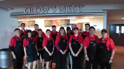 Fourteen Central Florida volunteers pose in front of the Crows Nest, their main concession stand during the 2016 season.
