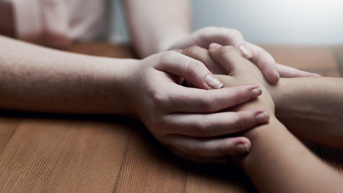 Shot of two people holding hands in comfort