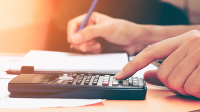 Close up young woman with calculator counting making notes at home, hand is writes in a notebook. Savings, finances, concept.