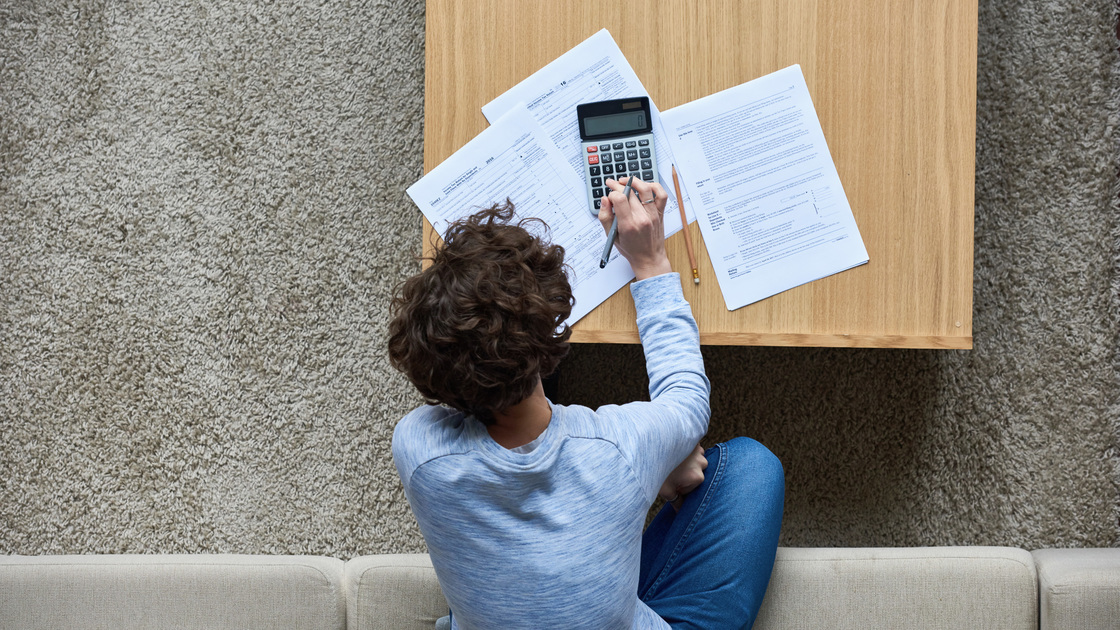 High angle view of curly woman calculating tax bill (16x9)