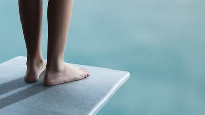 Young boy or girl is standing on a diving board and ready to jump